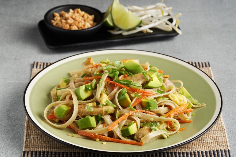 Avocado chicken pad thai dish with garnishes